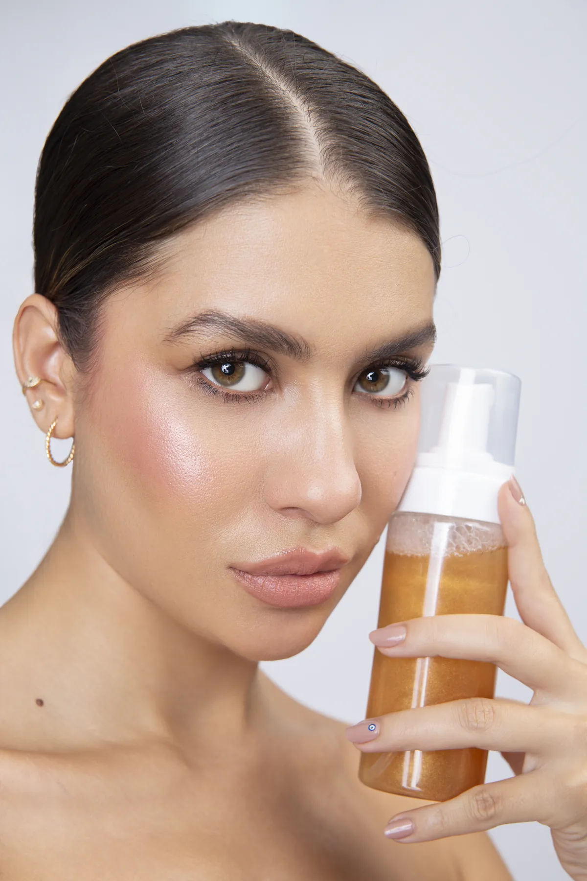 Modelo con piel luminosa sosteniendo la espuma facial GLOW de HONI