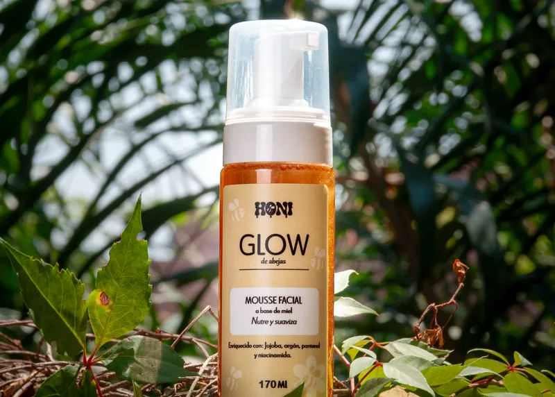 Espuma facial GLOW de HONI entre hojas, a pleno sol
